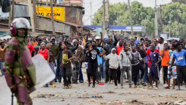 A riot police officer stands near supporters of Kenya's opposition leader Raila Odinga of the Azimio La Umoja (Declaration of Unity) One Kenya Alliance, during an anti-government protest against the imposition of tax hikes by the government, in Mathare settlement in Nairobi, Kenya, July 12, 2023. REUTERS/John Muchucha/File Photo